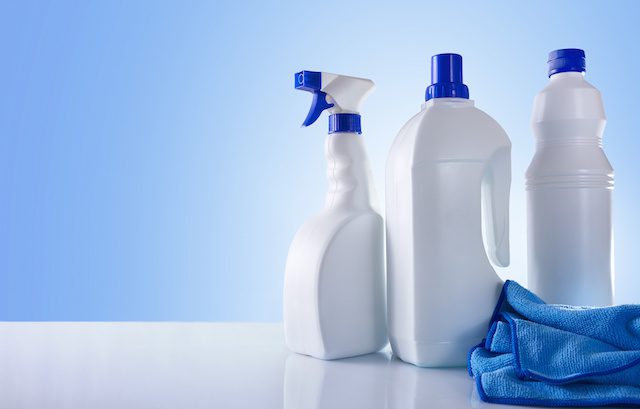 Cleaning products on white table and blue background overview. Front view. Horizontal composition.